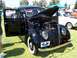2002 Ford Mustang - A black vintage car is displayed with its hood and driver's door open on a grassy field.