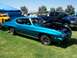 2002 Ford Mustang - A teal classic coupe is displayed with its hood open, alongside a dark blue pickup truck at an outdoor event.