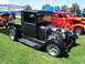 2002 Ford Mustang - A black hot rod pickup truck with a prominent exposed engine and custom wheels is displayed on a grassy field, with other vehicles in the b…