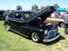 2002 Ford Mustang - A black classic sedan is displayed with its hood open at an outdoor car show.