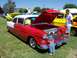 2002 Ford Mustang - A classic red and white Chevrolet sedan, likely a 1955 model, is displayed with its hood open, attracting the attention of a small child.