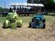 2002 Ford Mustang - Two custom hot rod cars are displayed outdoors with a band performing on a stage in the background.