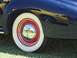 2002 Ford Mustang - Reflection of a yellow car is visible in the hubcap of a dark blue car with whitewall tires.