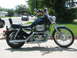 2001 Harley-Davidson Sportster Custom - A dark blue 2001 Harley-Davidson Sportster Custom motorcycle is parked on a sidewalk next to a street.