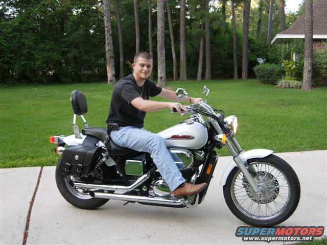 Guy on a white cruiser motorcycle with saddlebags parked on a driveway