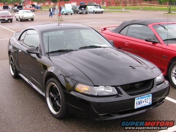 Black Ford Mustang GT parked next to a red convertible Mustang