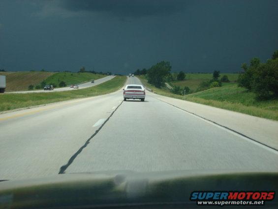 1992 Ford Crown Victoria driving on a highway under a dark, stormy sky