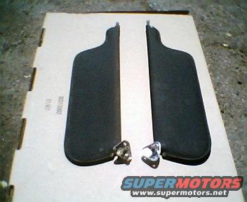 Two black sun visors with metal mounting brackets on a cardboard box