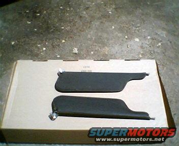 Two dark gray sun visors on a cardboard box, one above the other
