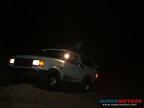 White 1989 Ford Bronco driving at night