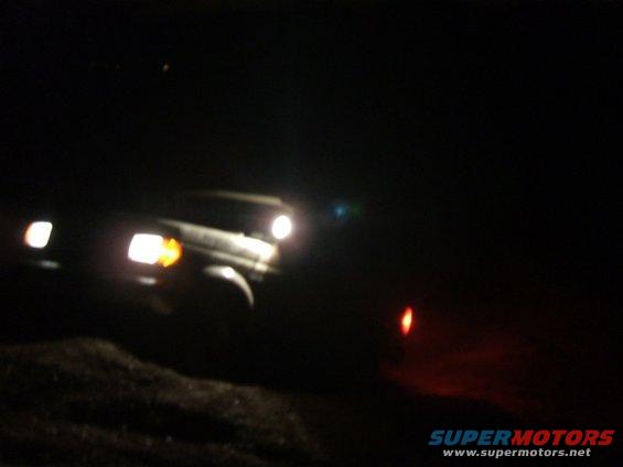 SUV with headlights on driving in the dark