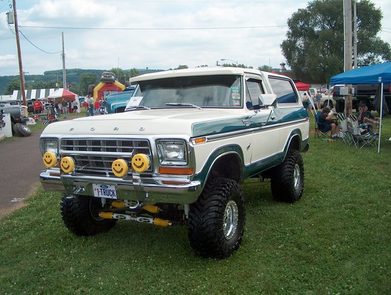 White and green 1978 Ford Bronco with smiley face lights and lifted suspension