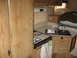 1996 Dodge 2500 - The interior of a camper shows a compact kitchen area with a two-burner stove, double sink, and wooden cabinetry.