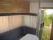 1996 Dodge 2500 - Interior view of a camper showing seating, curtains, and cabinets, with an open door revealing an outdoor scene.