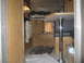 1996 Dodge 2500 - Interior view of a camper showing wood paneling, a table with a chrome pedestal, and a sleeping area with blankets.