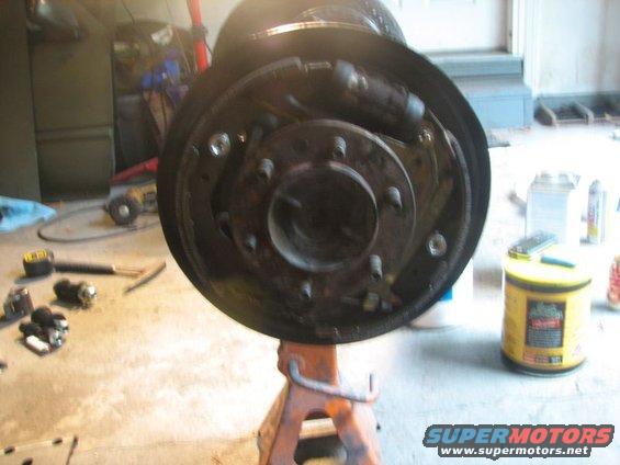 Brake drum assembly on an orange jack stand, with tools on the floor