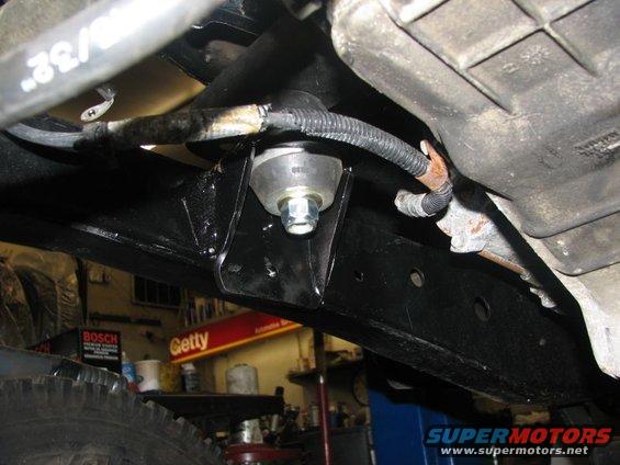 Close-up of underbody suspension mount with visible bolt and wiring