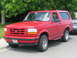 2001 Harley-Davidson Sportster Custom - A red Ford Bronco is parked on a residential street with trees in the background.