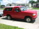 2001 Harley-Davidson Sportster Custom - A red Ford Bronco is parked curbside on a sunny day, with houses in the background.