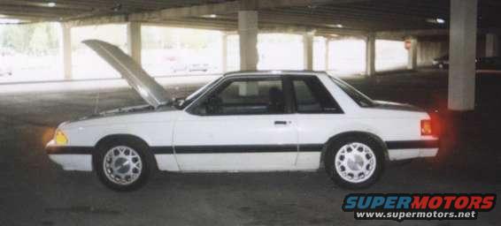 White 1992 Ford Mustang coupe with hood open, parked under a concrete structure