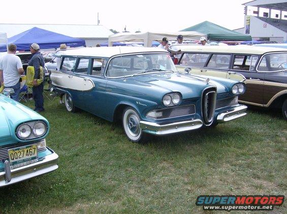 Blue and white 1958 Edsel Bermuda station wagon parked on grass with other cars