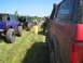 1989 Ford Bronco - Several off-road vehicles are lined up on a grassy area on a sunny day, covered in mud.