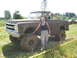1989 Ford Bronco - A woman poses next to a heavily mud-caked Chevrolet pickup truck during an outdoor event.
