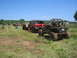 1989 Ford Bronco - Several off-road vehicles are gathered in a grassy field under a clear blue sky, ready for a mud bogging event.