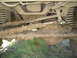 1989 Ford Bronco - The undercarriage of a vehicle is heavily coated in mud, obscuring details of its make and model.