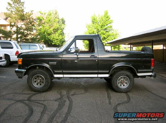 Side view of black 1988 Ford Bronco with white trim and spare tire on back
