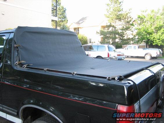 1988 Ford Bronco with black tonneau cover, parked near other vehicles