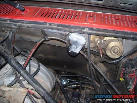 Close-up of engine bay with various wires, hoses, and mechanical parts visible