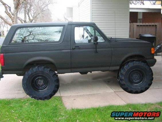 Dark matte SUV with oversized tires, side view. The body style suggests a 1992 model year