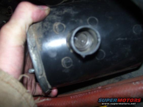 Hand holding a black automotive part with a threaded opening