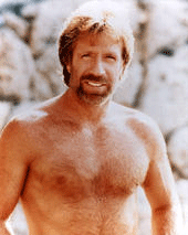 Man with beard and chest hair, smiling, outdoors with rocks in background