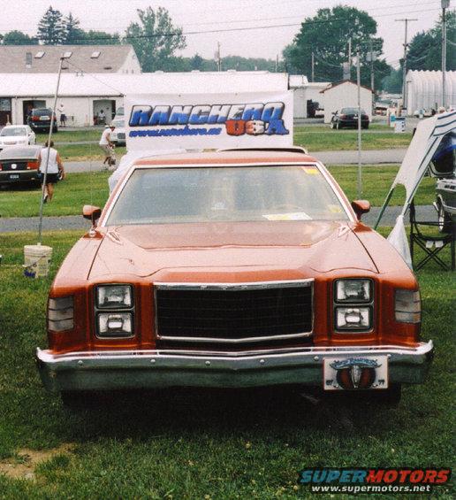 Orange pickup truck front view with a black grille and a license plate frame with a bull skull