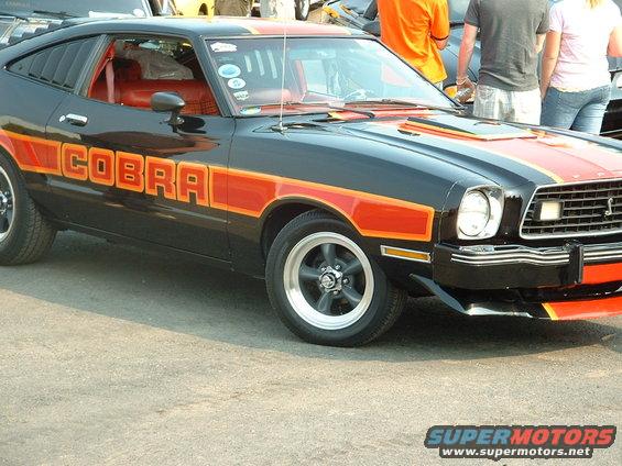 Black 1978 Ford Mustang II Cobra with orange stripes and lettering, side view