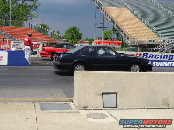 Black coupe drag racing, side view, with number 84 on the rear quarter window
