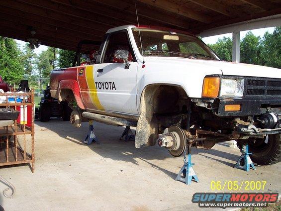 Toyota pickup truck on jack stands with wheels removed, undergoing maintenance