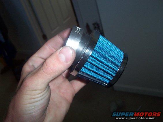 Hand holding a blue cone air filter with a metal clamp