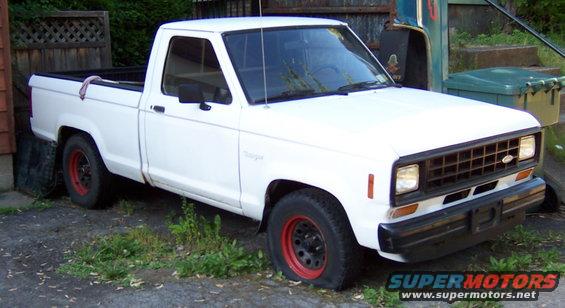 White pickup truck with red rims parked outside