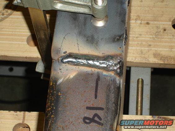Close-up of a metal bracket with a weld bead and the number '18' written on it