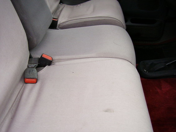 Car interior showing light-colored front seats with seatbelts. Darker gray headrest visible
