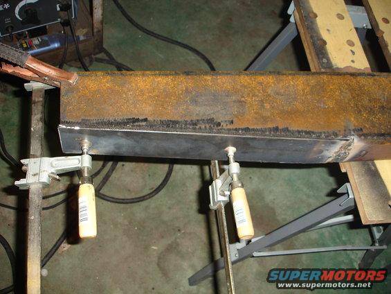 Metal beam being welded, clamped in place