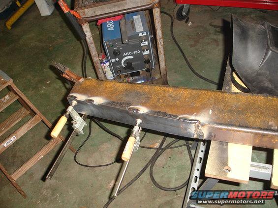 welding a rusty metal beam with clamps and a welding machine nearby
