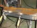 1989 Ford Bronco - Metal beam undergoing welding repairs, with clamps and a welding machine visible.
