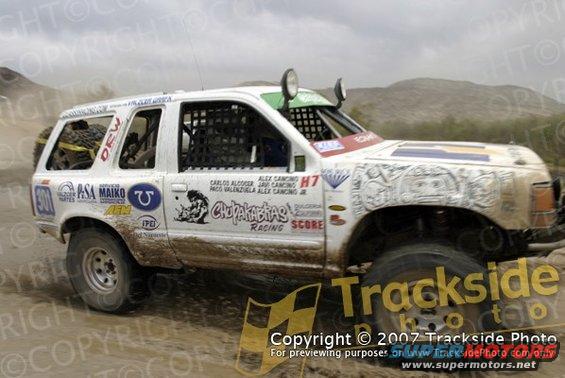 White off-road SUV with racing decals, mud-splattered, driven on a dirt track