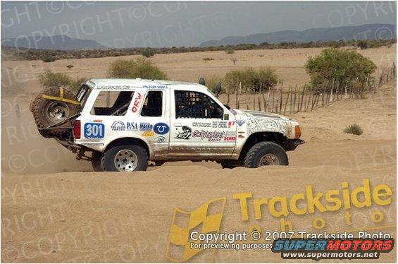 White SUV with spare tire on rear, number 301, driving in sand