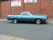 1970 Ford Ranchero - Side view of a blue 1970 Ford Ranchero parked on a street in front of a brick building with an auto service sign.