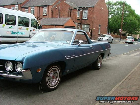 Blue 1970 Ford Ranchero parked on street, van and other cars in background